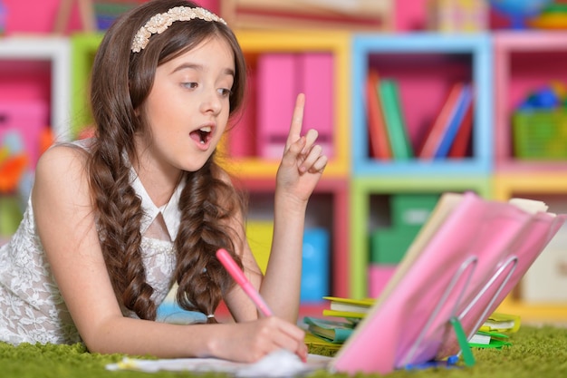 Niña linda haciendo la tarea en la mesa en casa