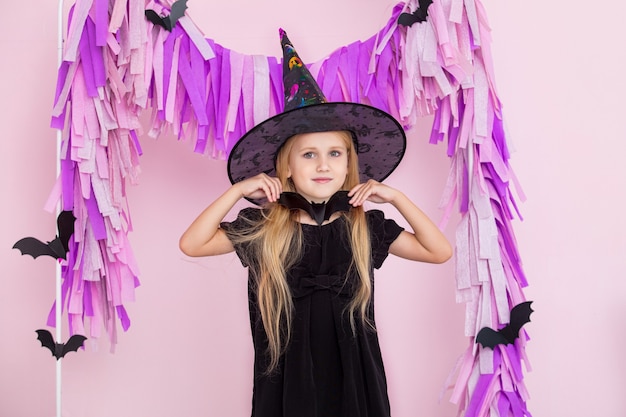 Niña linda hermosa en traje de carnaval de brujas en decoraciones de Halloween de moda