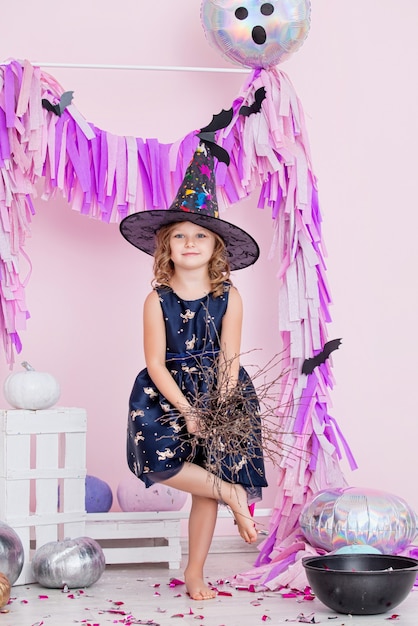 Niña linda hermosa en traje de carnaval de brujas en decoraciones de Halloween de moda