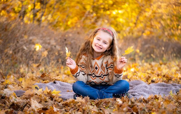 Niña linda con hojas amarillas al aire libre