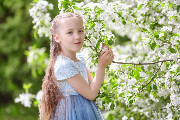 Niña linda en jardín floreciente de manzano en la primavera