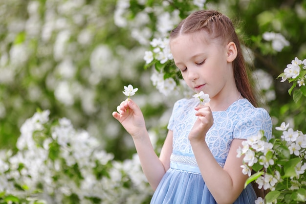 Niña linda en jardín floreciente de manzano en la primavera