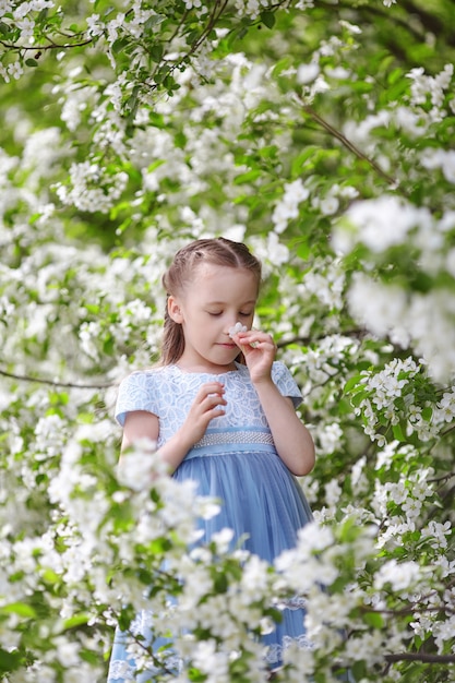 Niña linda en jardín floreciente de manzano en la primavera