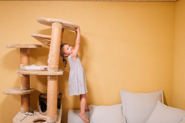 Niña linda juega con una casa de gato dolorido.