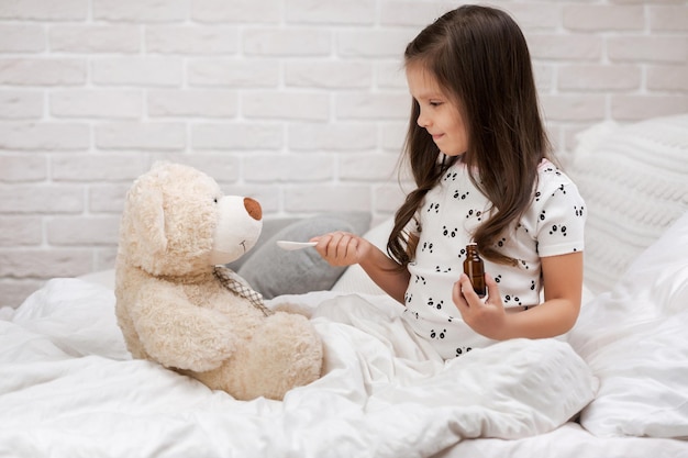 Niña linda jugando al doctor con osito de peluche