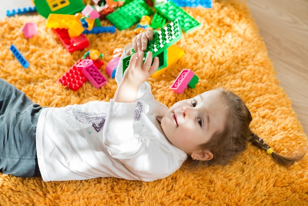 Niña linda jugando con bloques de colores en casa