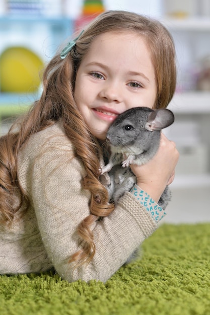 Niña linda jugando con chinchilla en casa