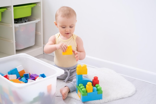 Niña linda jugando en un colorido constructor de plástico en el suelo en casa Desarrollo de la primera infancia