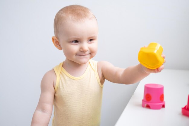 Niña linda jugando con coloridos juguetes de plástico en casa Desarrollo de la primera infancia