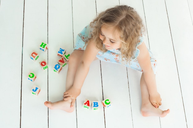 Niña linda jugando con cubos abc en el interior