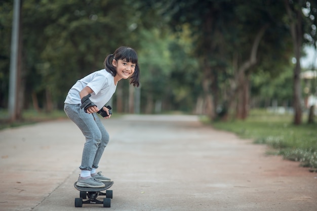 Niña linda jugando patineta o patín de surf en el parque de patinaje