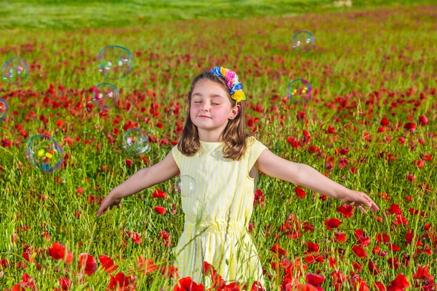 Niña linda jugando con pompas de jabón en la naturaleza