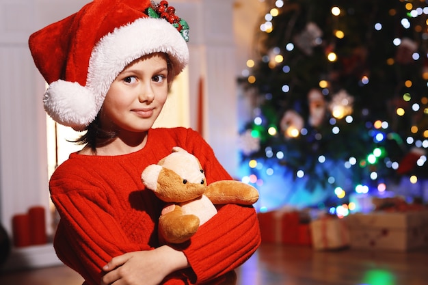 Niña linda con juguete esperando la noche de Navidad