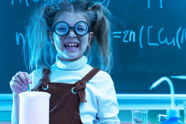 Niña linda durante la lección de química en la escuela