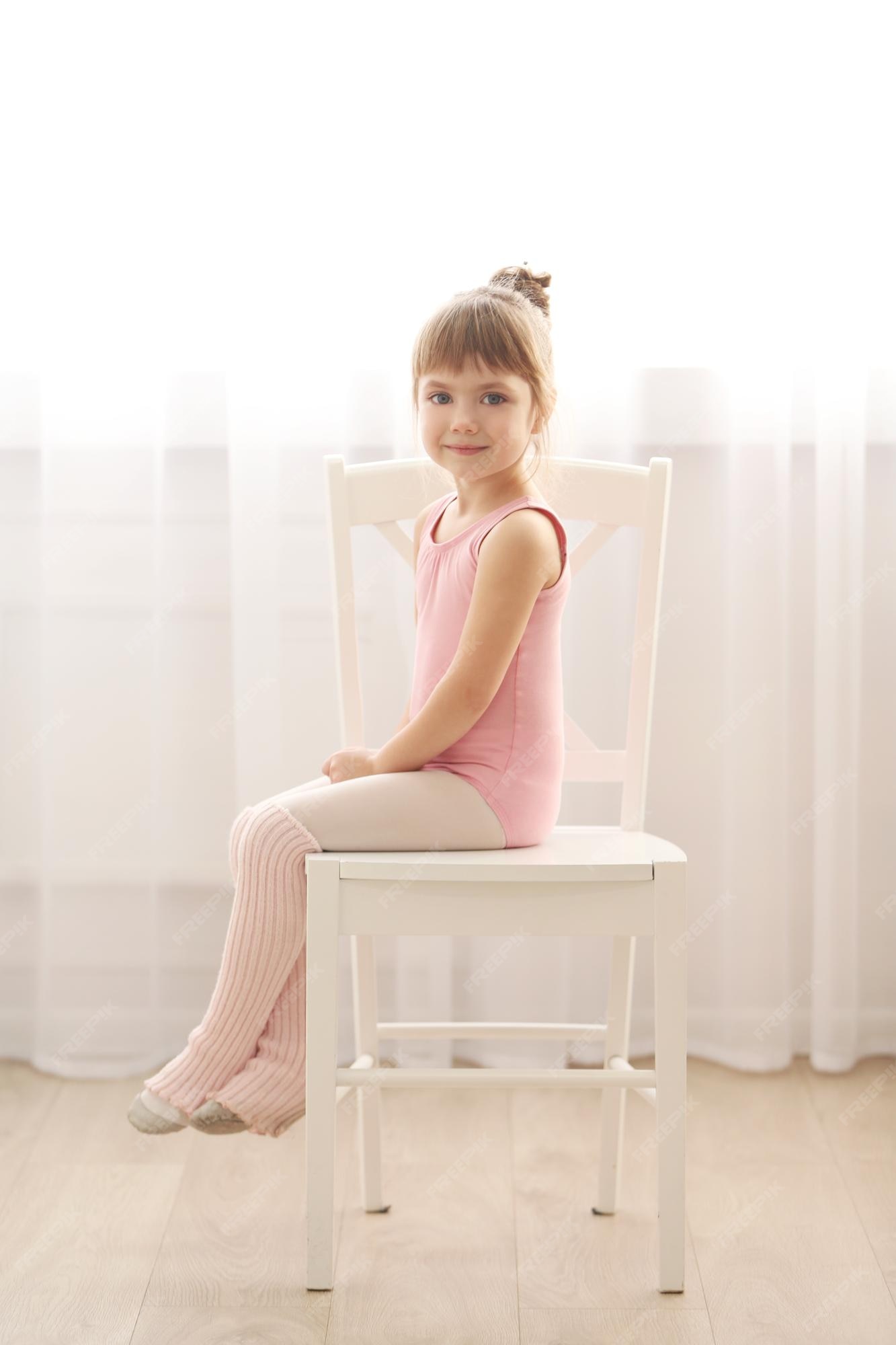 Niña linda en leotardo rosa sentada en una en estudio de baile | Foto Premium