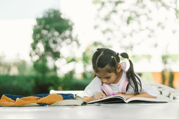 Una niña linda leyendo un libro en el jardín concepto de educación