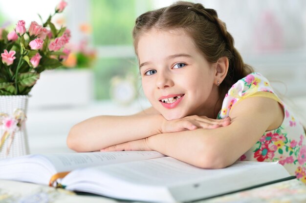 Niña linda leyendo un libro en la mesa en casa