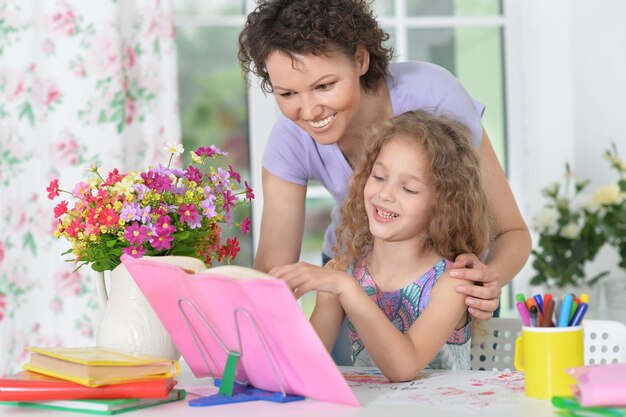 Niña linda leyendo un libro con su madre