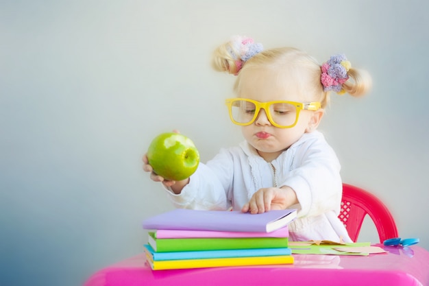 Niña linda con libros y manzana verde