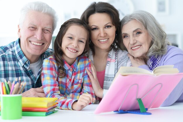 Niña linda con madre y abuelos estudiando