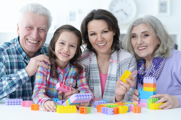 Niña linda con madre y abuelos jugando juntos en casa