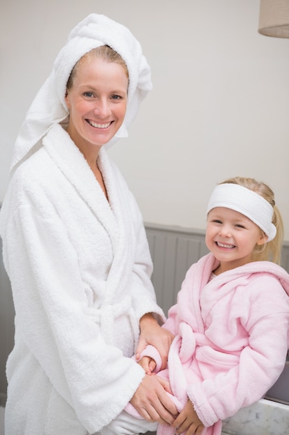 Niña linda con madre en batas de baño