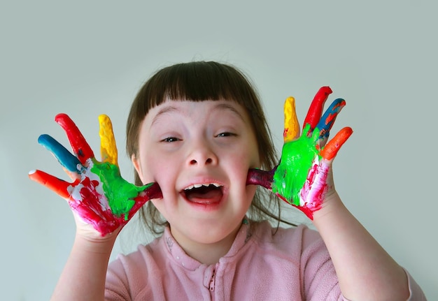 Foto niña linda con las manos pintadas. aislado sobre fondo gris.