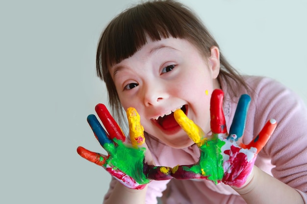 Niña linda con las manos pintadas. Aislado sobre fondo gris.