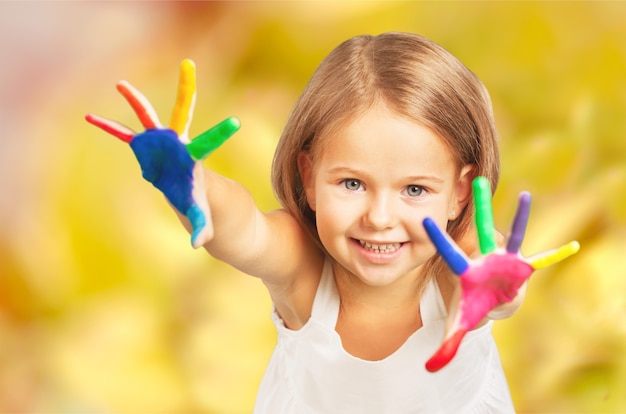 Niña linda con manos pintadas de colores sobre fondo claro