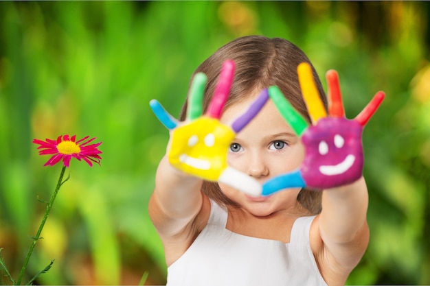 Niña linda con las manos pintadas de colores sobre fondo