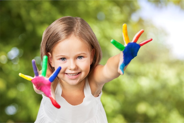 Niña linda con las manos pintadas de colores sobre fondo