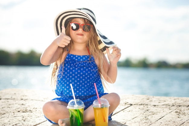 Niña linda en el mar. Chica del sombrero en verano. Adorable niño en la costa.