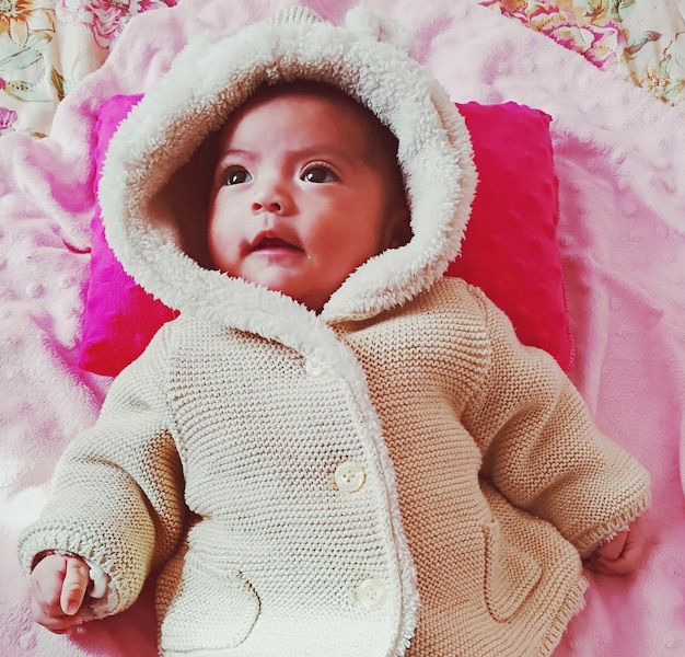 Foto niña linda mirando hacia otro lado mientras está acostada en la cama en casa