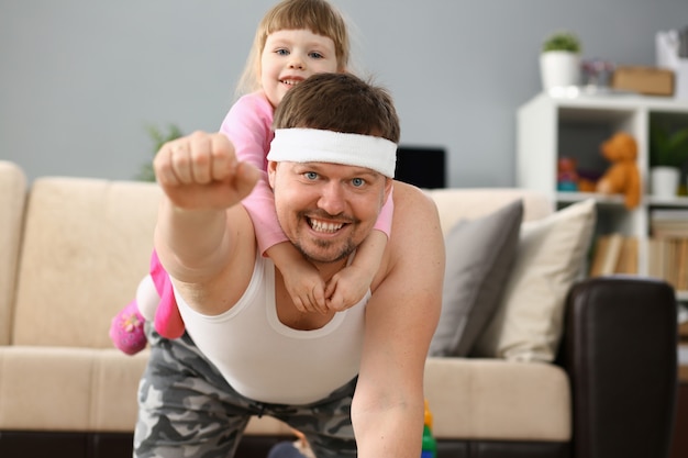 Niña linda montando a su padre en casa jugando