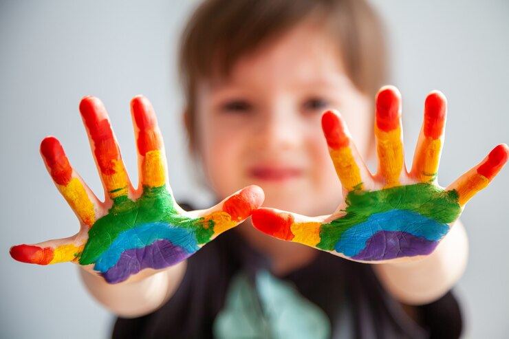 Niña linda mostrando sus manos con arco iris pintado sobre ellos