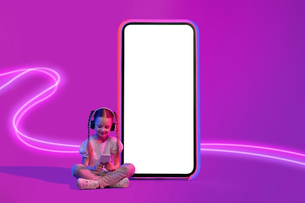 Niña linda niña feliz usando teléfono inteligente y auriculares inalámbricos