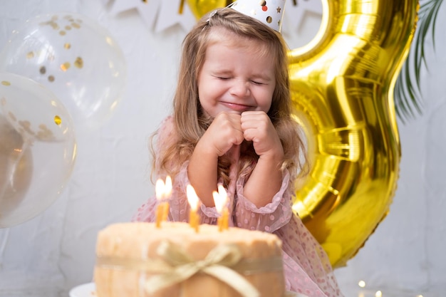 Niña linda niña soplando velas en la torta de cumpleaños y celebrando el cumpleaños