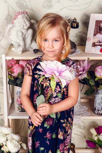 Niña linda del niño con flores de primavera, niña feliz con cesta de flores.