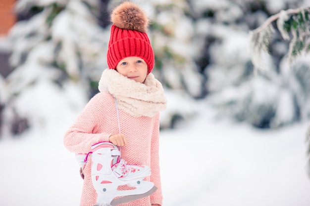 La niña linda del niño va a patinar al aire libre.