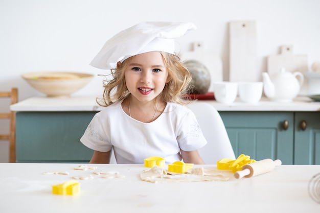 Niña linda panadero en cocina con ingredientes para hornear