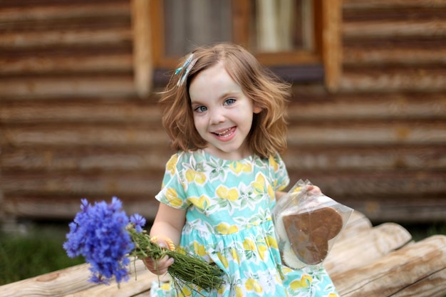 Niña linda en el parque de otoño con ramo de flores azules