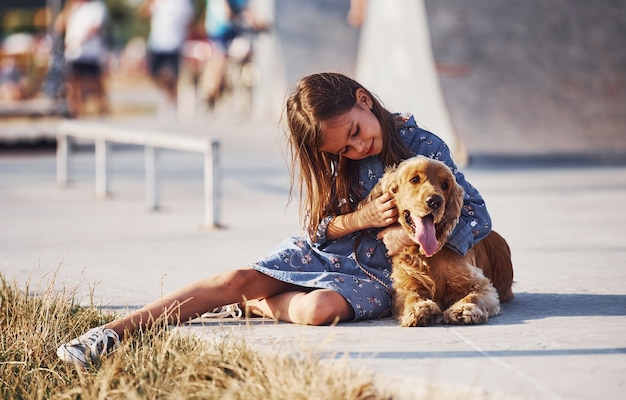 Niña linda pasear con su perro al aire libre en un día soleado