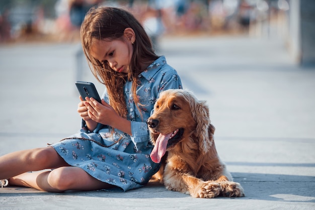 Niña linda pasear con su perro al aire libre en un día soleado