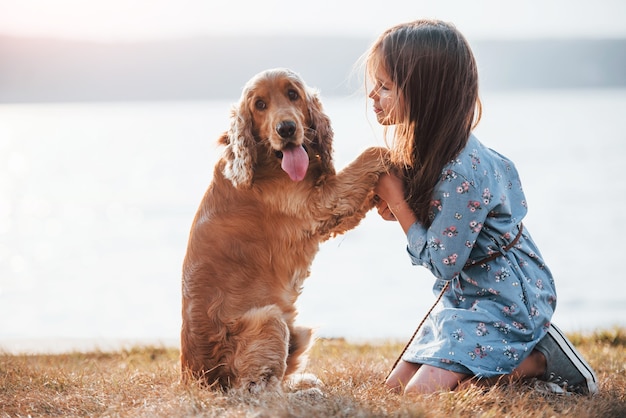 Niña linda pasear con su perro al aire libre en un día soleado