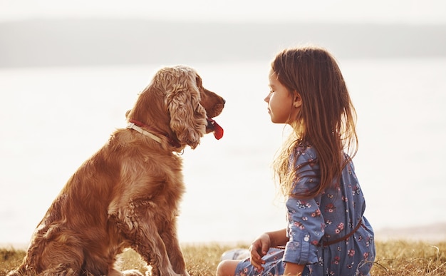 Niña linda pasear con su perro al aire libre en un día soleado