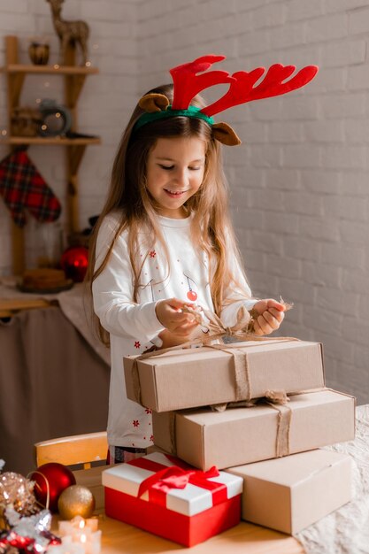 una niña linda en pijama en casa empacando regalos para Navidad y Año Nuevo