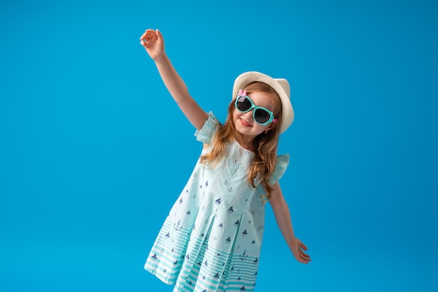 Niña linda en poses de vestido, sombrero y gafas de sol