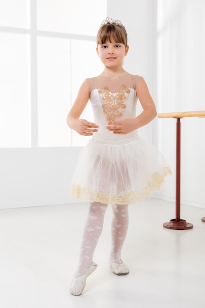 Niña linda practicando ballet y mirando a la cámara.