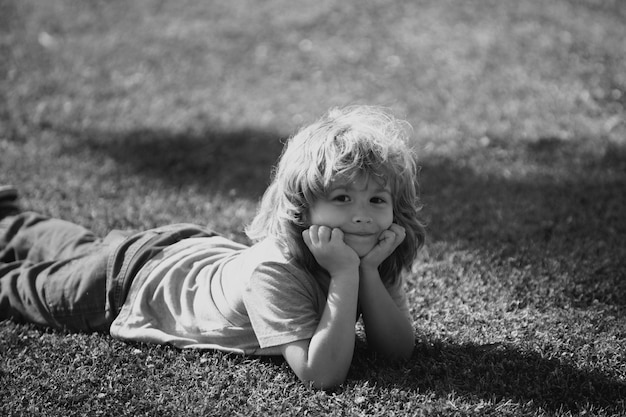 Niña linda en el prado en el día de la primavera niño de la infancia feliz acostado en la hierba niño lindo niño disfrutar