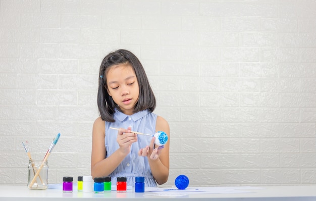 Niña linda que aprende el modelo de fabricación del sistema solar con pintura en bola de espuma